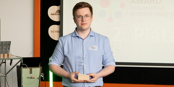 Maximilian Krebs hält eine Trophäe für den TU innovation award