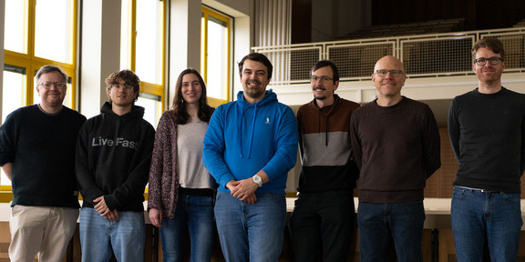 Seven smiling people in a lecture hall