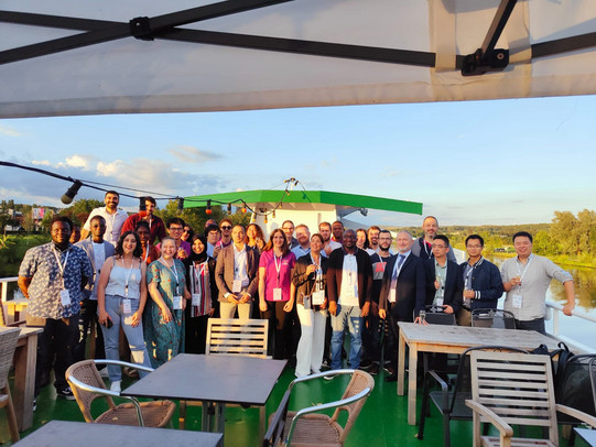 A large group of conference organizers and researcher on the upper deck of a boat smiling for the camera. 