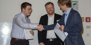 Der Dekan der Fakultät Informatik übergibt die Urkunde zum Nachhaltigkeitspreis an Maximilian Krebs