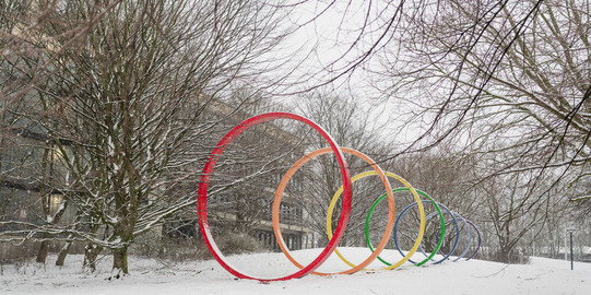 The colorful steel spectral rings stand on a snow-covered meadow on the North Campus.