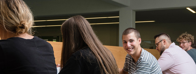 Rear view of five students. One of them is smiling at the camera.